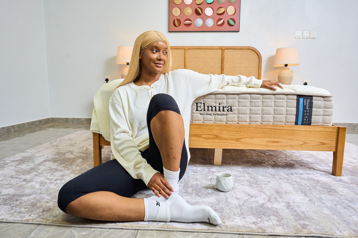 A woman sits on a gray rug in front Elmira mattress